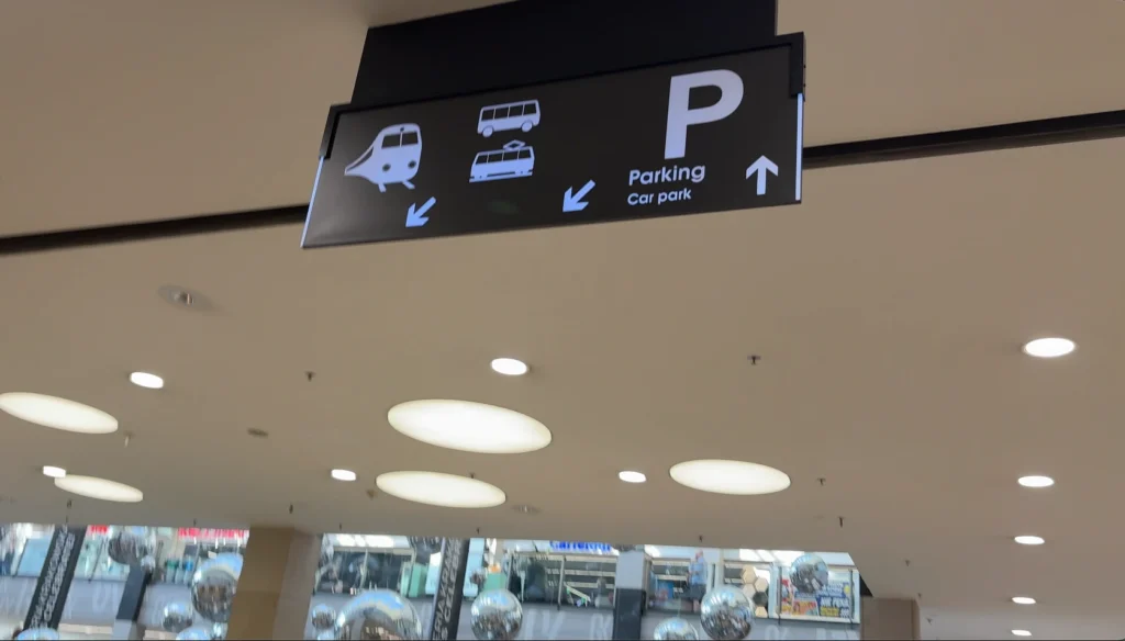 Señalización interna hacia trenes y autobuses dentro de Galeria Krakowska